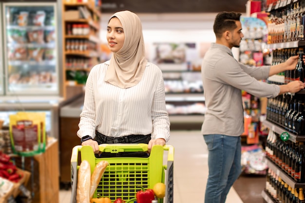 Middle eastern lady wearing hijab shopping groceries in modern supermarket