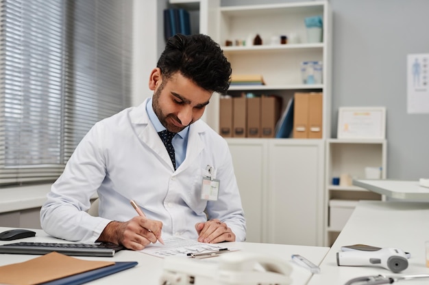 Middle eastern male doctor filling in medical card