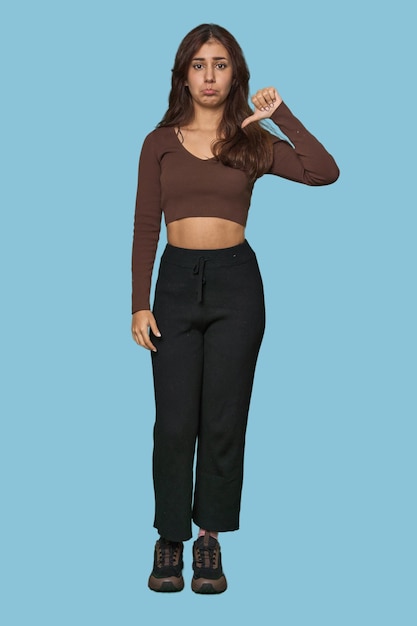 Middle Eastern woman full body studio showing a dislike gesture thumbs down Disagreement concept