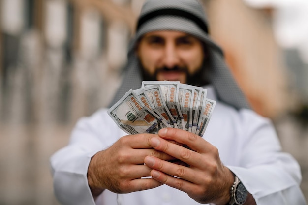 Middle eastern young man holding dollars in hands