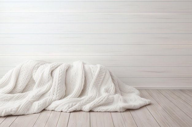 In the middle of the empty space sits a white knitted blanket on a white wooden floor with text writ