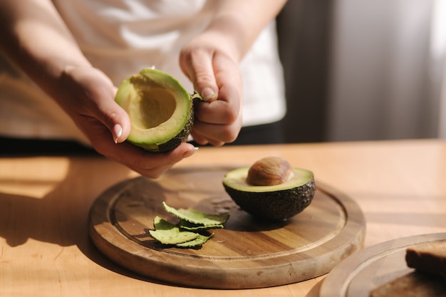 Middle selection of female pill an avocado on wooden board at home. Vegetarian food concept.