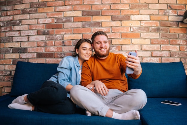 Middle shot portrait of happy cheerful young couple having online webcam chat with via video call on mobile phone