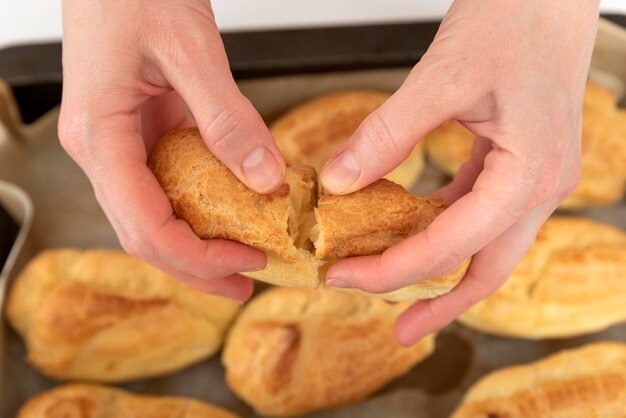 Middle of workpiece for profiteroles in hands of Chef Puffs popovers eclair Close up