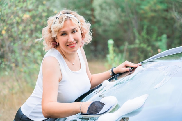 A middleaged blonde woman can windscreen a car