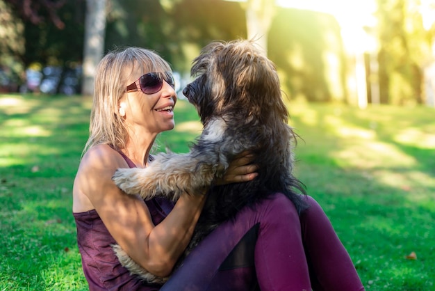 Middleaged blonde woman with glasses cuddling her Catalan shepherd dog Love for animals Pet care