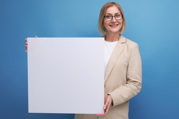 Middleaged business concept smiling woman in jacket demonstrating information board with mocup on