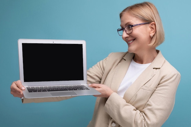 Middleaged business concept woman in a jacket with a laptop to work on a studio background with copy