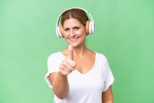 Middleaged caucasian woman over isolated background listening music and with thumb up