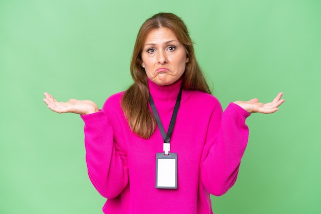 Photo middleaged caucasian woman with id card over isolated background having doubts while raising hands