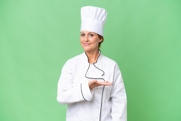 Middleaged chef woman over isolated background presenting an idea while looking smiling towards