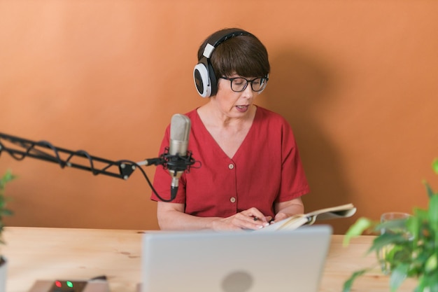 Middleaged female radio presenter talking into the microphone and reading news radio broadcast onli