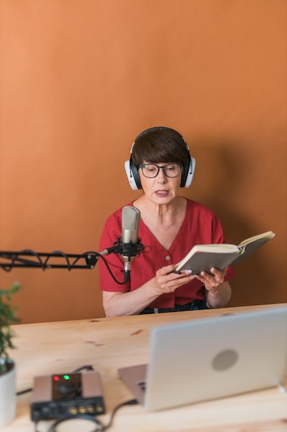 Middleaged female radio presenter talking into the microphone and reading news radio broadcast onlin