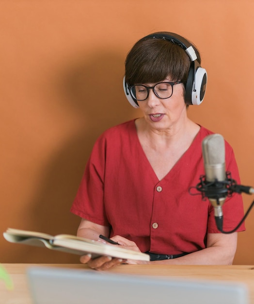 Middleaged female radio presenter talking into the microphone and reading news radio broadcast online concept