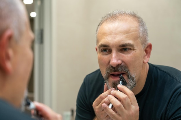 Middleaged handsome man using razor in bathroom