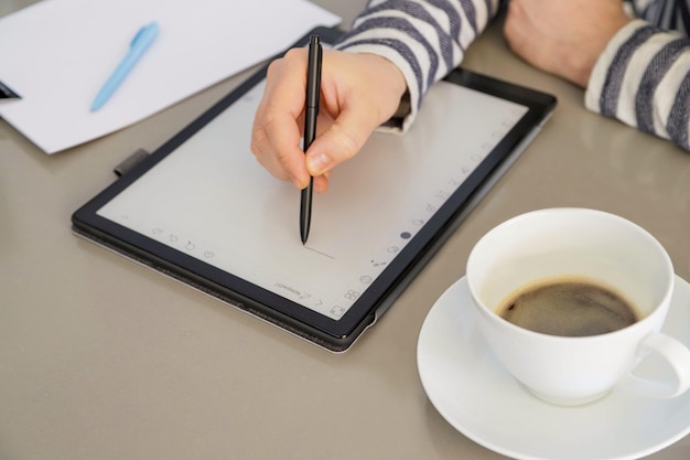 middleaged man reading an ebook and drinking coffee at home hands closeup