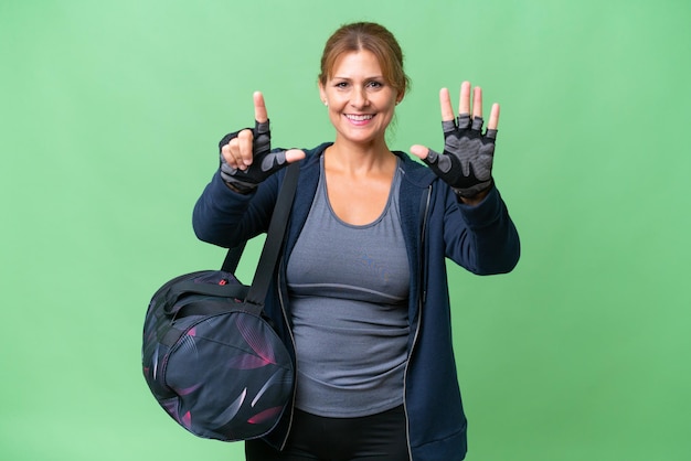 Middleaged sport woman with sport bag over isolated background counting seven with fingers