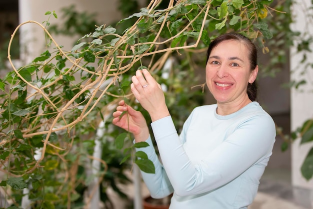 Middleaged woman caring for a plant looking at the camera and smiling