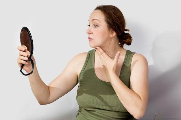 A middleaged woman looks worriedly at herself in the mirror