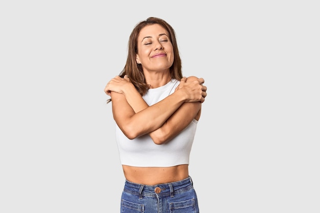 Middleaged woman portrait in studio setting hugs smiling carefree and happy