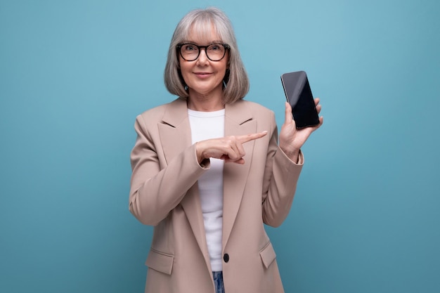 Middleaged woman in a stylish bow with a smartphone in her hands on a studio background with copy