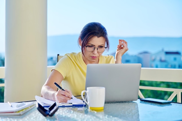 Middleaged woman working in a home office on a terrace