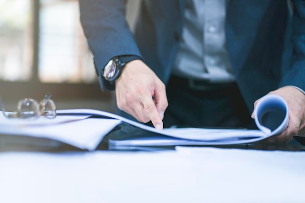 Midsection of businessman with documents on desk in office