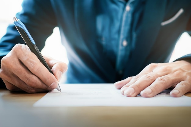 Photo midsection of businessman writing on paper at desk