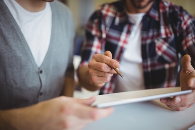 Midsection of businessmen using digital tablet in office