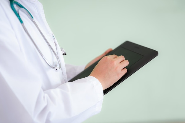 Photo midsection of doctor using digital tablet while standing in office