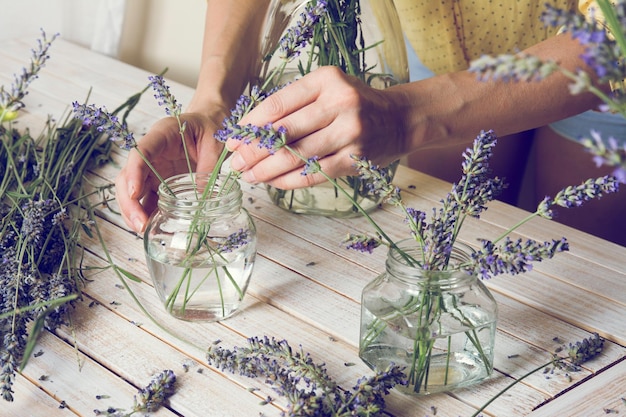 Photo midsection of florist arranging lavender flowers in jar on table