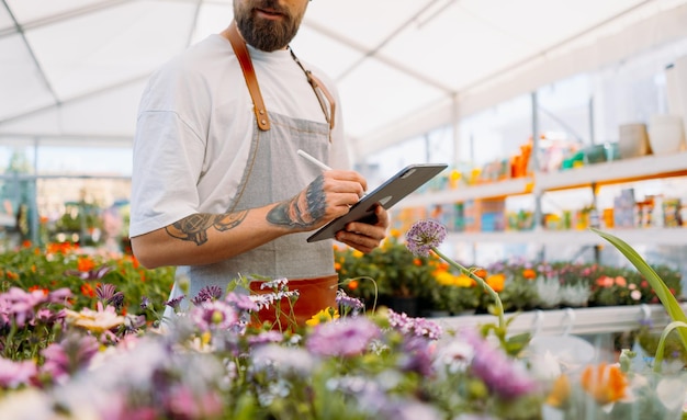 Midsection of gardener using tablet in garden centre high quality photo