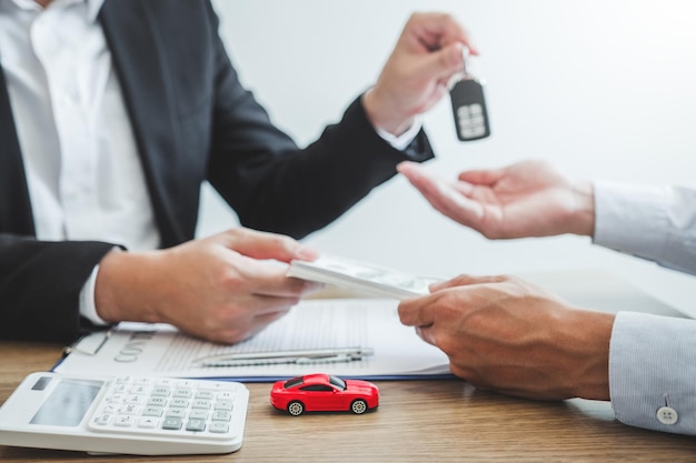 Photo midsection of insurance agent giving key while receiving money from customer