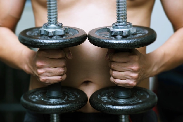 Photo midsection of man holding dumbbells