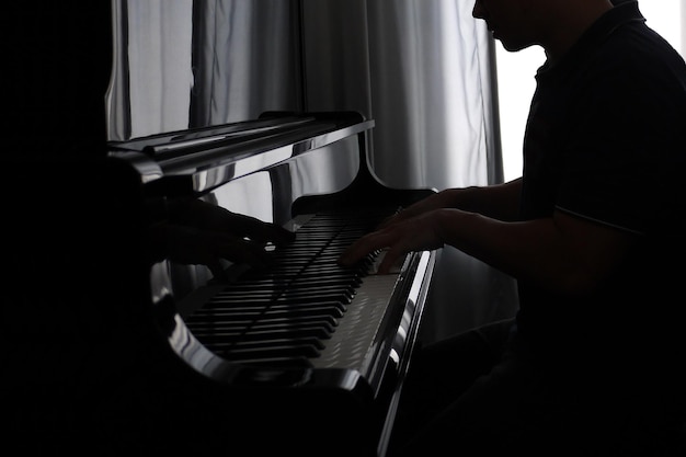 Photo midsection of man playing piano in dark at home