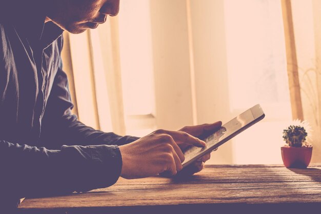 Photo midsection of man using digital tablet on table at home