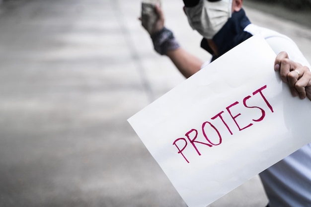 Photo midsection of man with text on paper throwing stone while standing outdoors