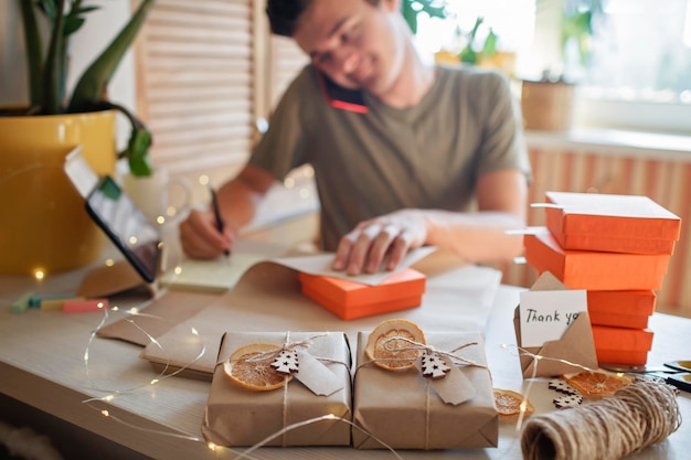 Photo midsection of man writing in diary while packing gifts