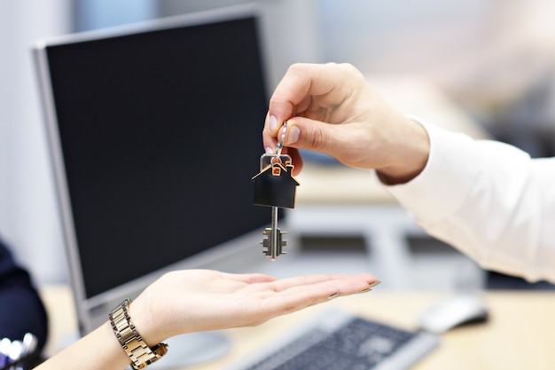 Midsection of real estate agent and buyer hands with keys in the office