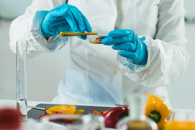 Photo midsection of scientist experimenting on bell peppers