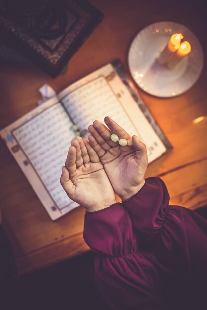 Midsection of woman holding prayer beads by koran