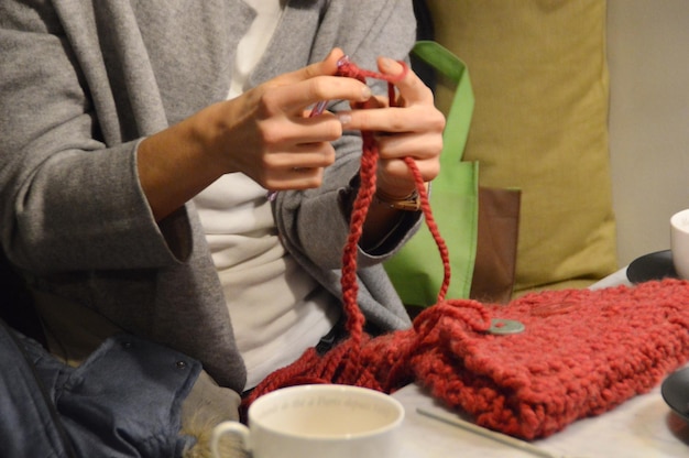 Photo midsection of woman knitting purse while sitting at home