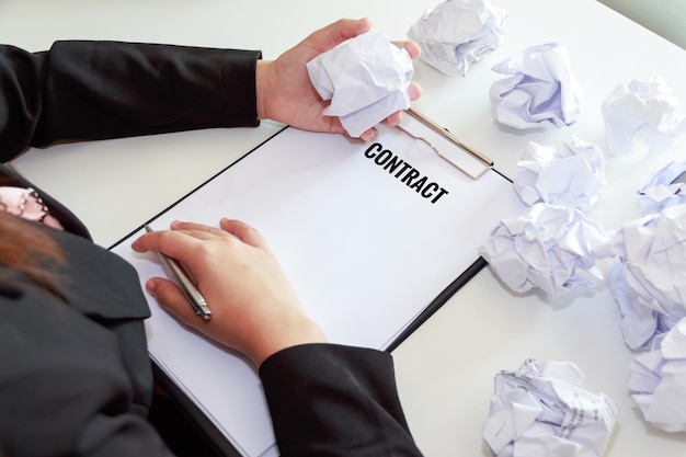 Photo midsection of woman with contract by crumpled papers at table