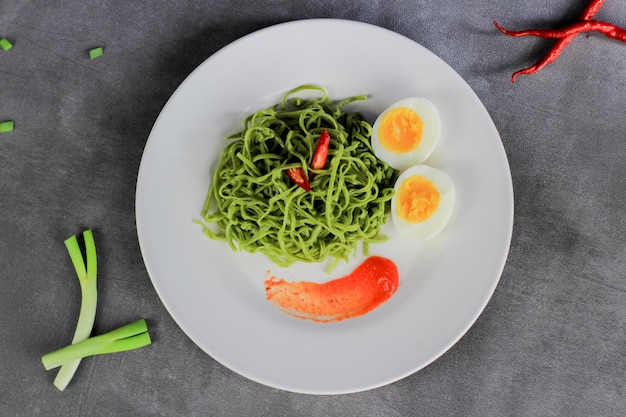 Mie Goreng Fried noodles served with fried eggs and vegetables on a plate