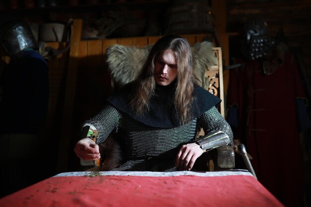 A mighty hero with long hair in chain mail armor in an ancient hall Medieval warrior in the knight's chambers