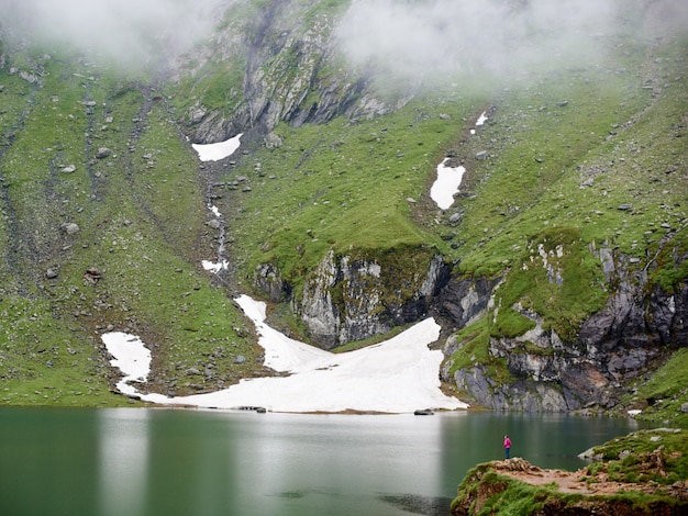 Mighty mountains are covered with fog and the lake at the foot