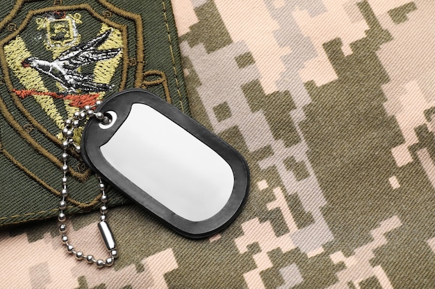 Military ID tag and patch on pixel Ukrainian camouflage top view Space for text