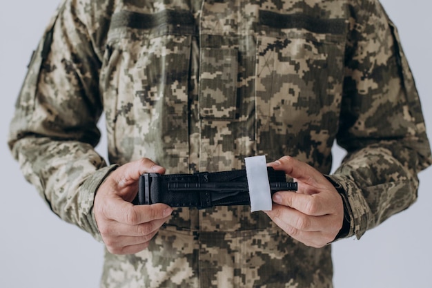 A military man demonstrates a combat medical tourniquet to stop blood during first aid Instructions for combat tactical equipment