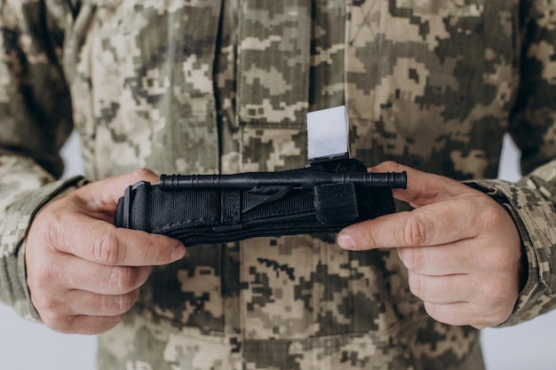 A military man demonstrates a combat medical tourniquet to stop blood during first aid Instructions for combat tactical equipment