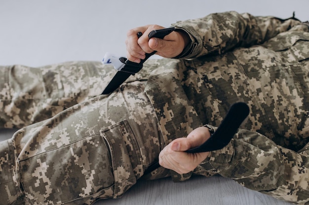 A military man demonstrates a combat medical tourniquet to stop blood during first aid Instructions for combat tactical equipment